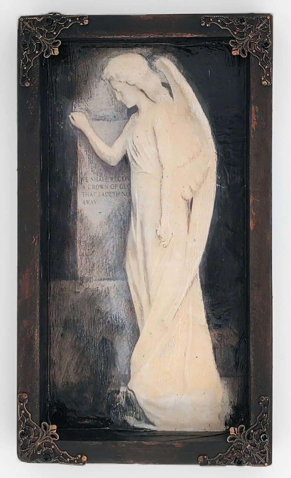 An angel shadowbox — a mourning angel in a distressed frame with ornate metal corners